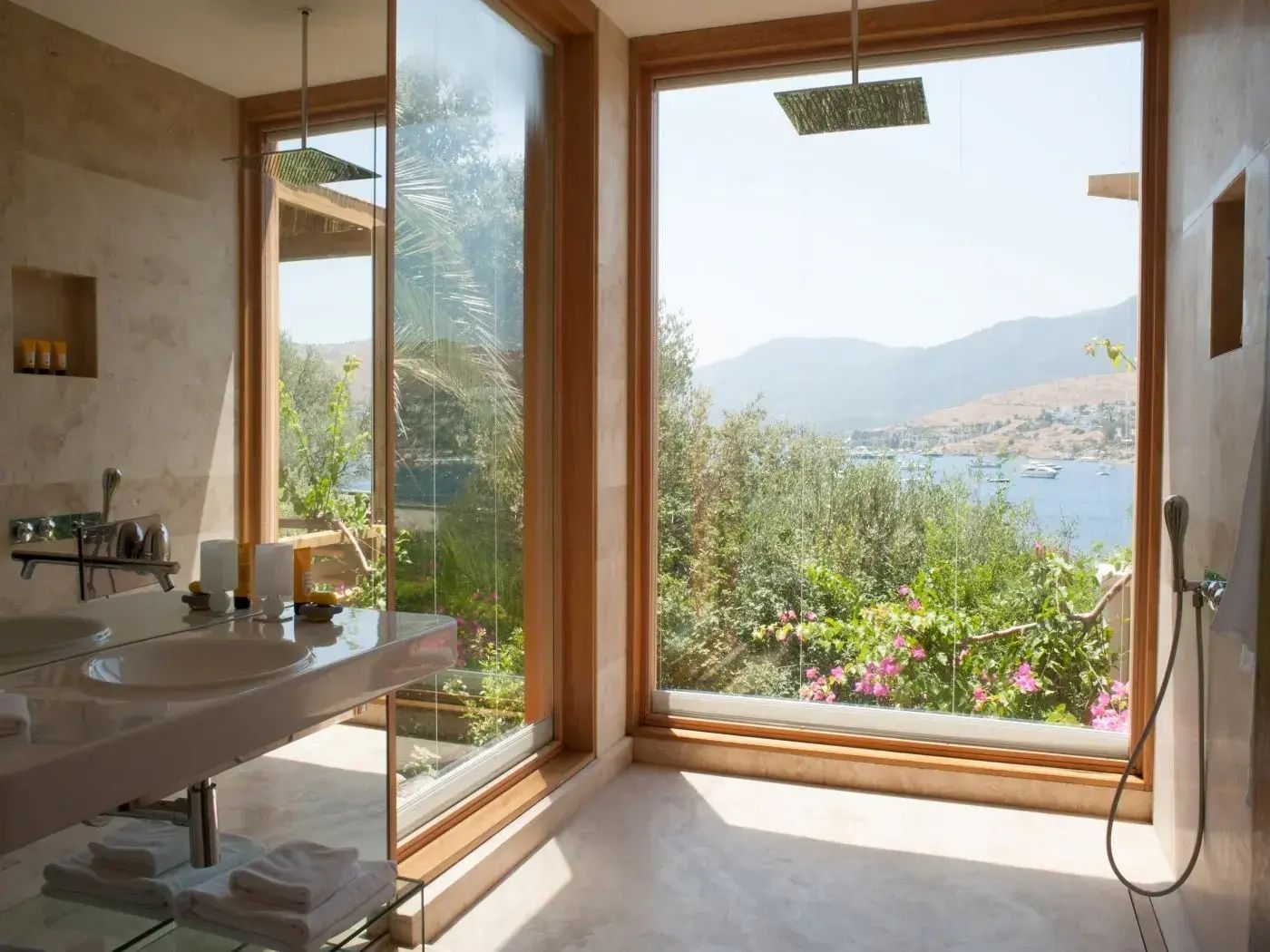Badezimmer mit großem Panoramafenster, Waschtisch und Ausblick auf Natur und Meer.