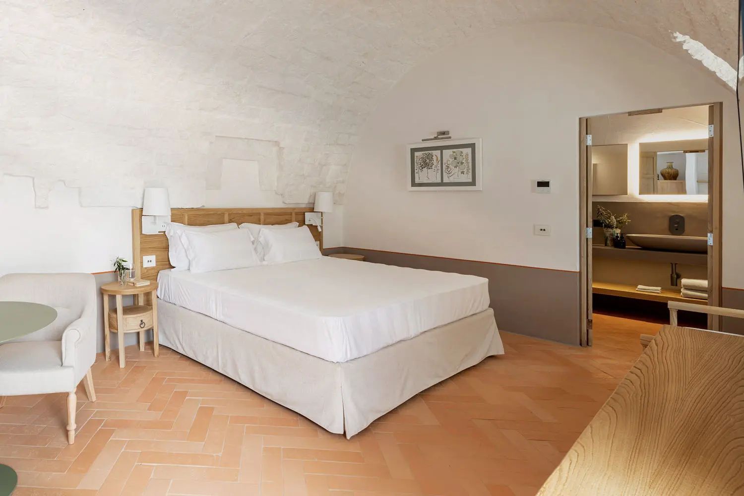 Schlafzimmer mit Doppelbett, hellem Gewölbe und Terrakotta-Fliesenboden