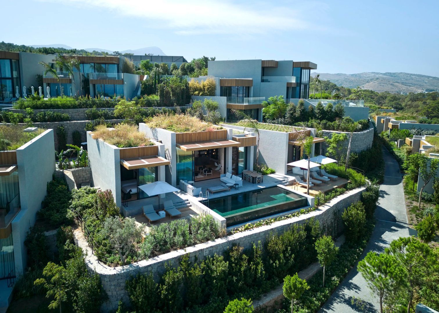 Moderne Villen am Hang mit bepflanzten Dächern, Terrassen und privatem Pool.