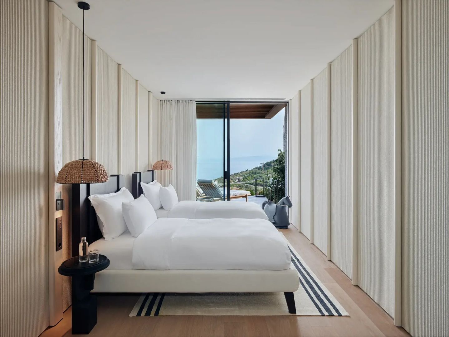 Helles Schlafzimmer mit zwei Einzelbetten und Zugang zur Terrasse mit Meerblick