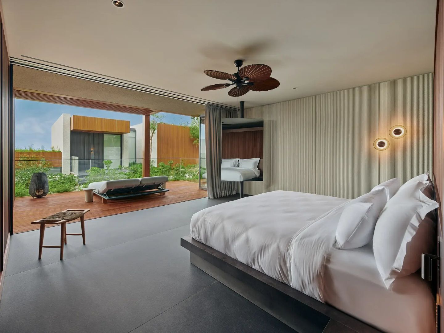 Moderner Schlafbereich mit großem Doppelbett und Übergang zur holzvertäfelten Terrasse.