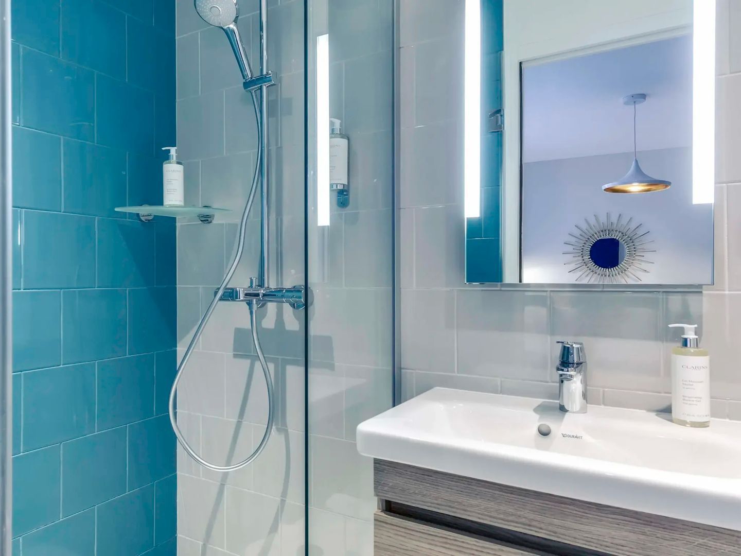 Modernes Badezimmer mit einer Glasdusche, blauen Fliesen und einem Waschbecken.