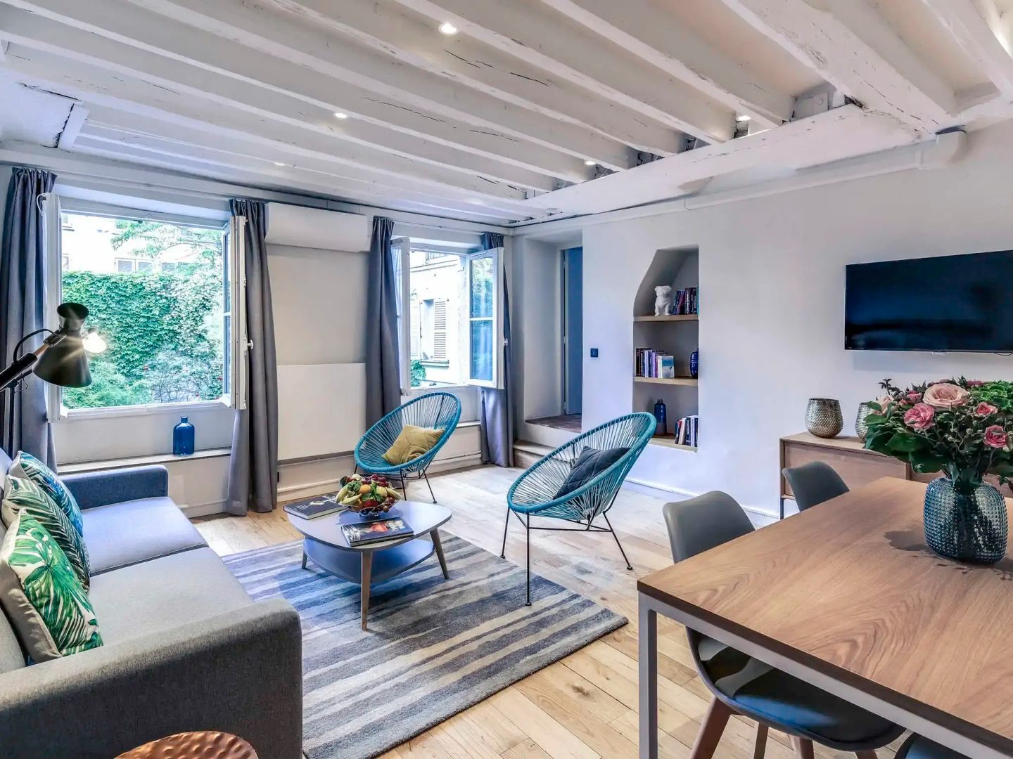 Wohnbereich mit zwei blauen Sesseln, einem Sofa und Fenster zum Garten