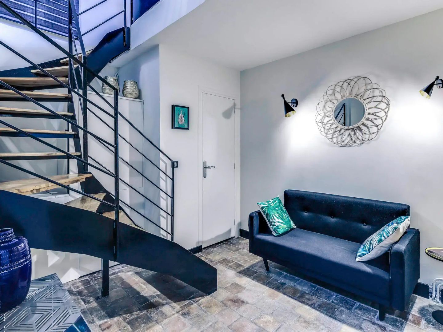 Dunkelblaues Sofa und Wendeltreppe aus Metall in einem Apartment