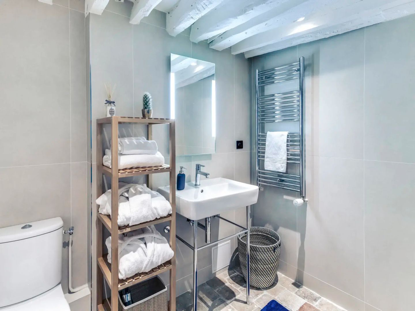 Modernes Badezimmer mit weißem Waschbecken, Holzregal und Handtuchwärmer