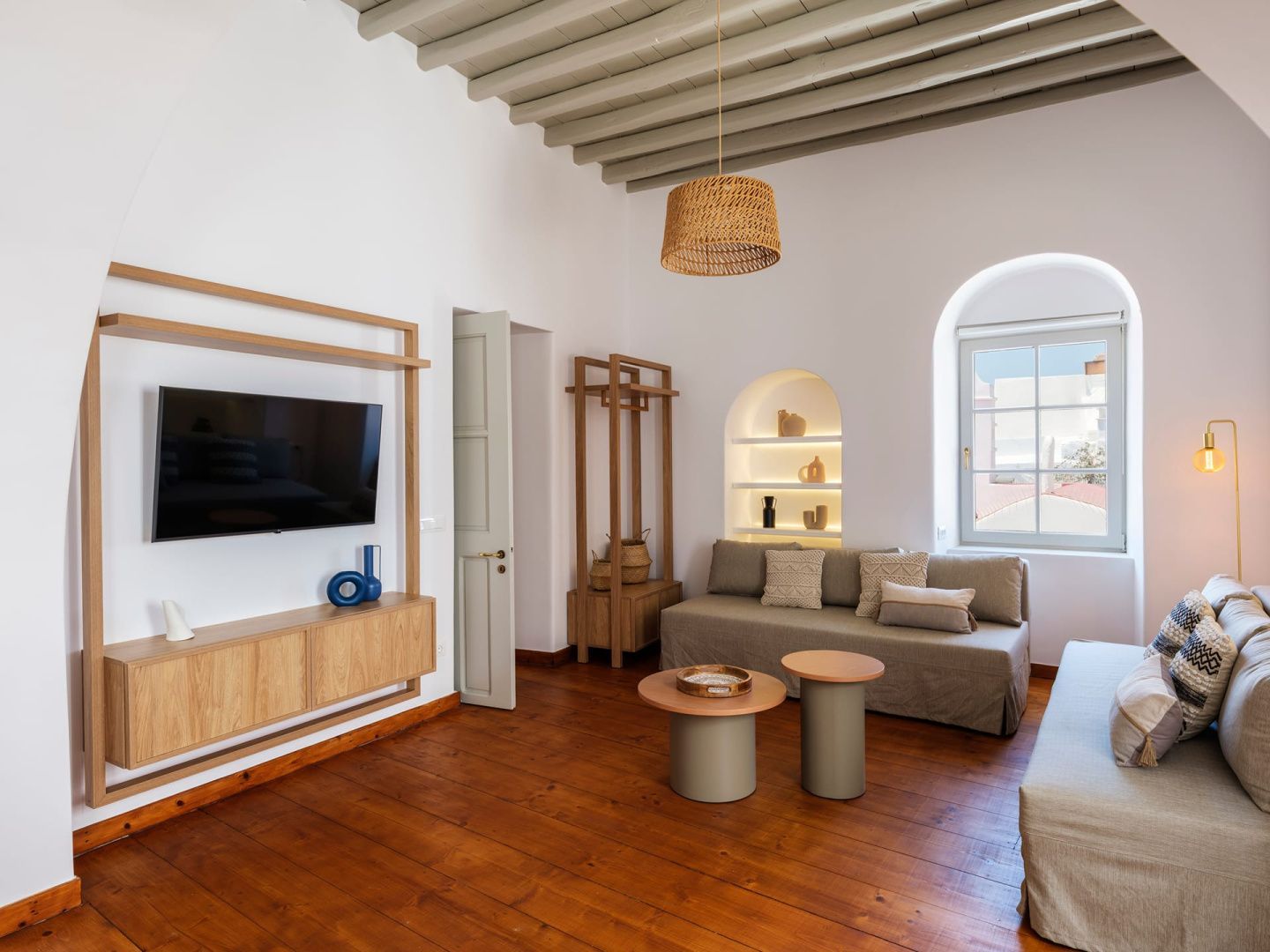 Wohnzimmer mit Flachbildfernseher an einer Holzwand und beigefarbenem Sofa.