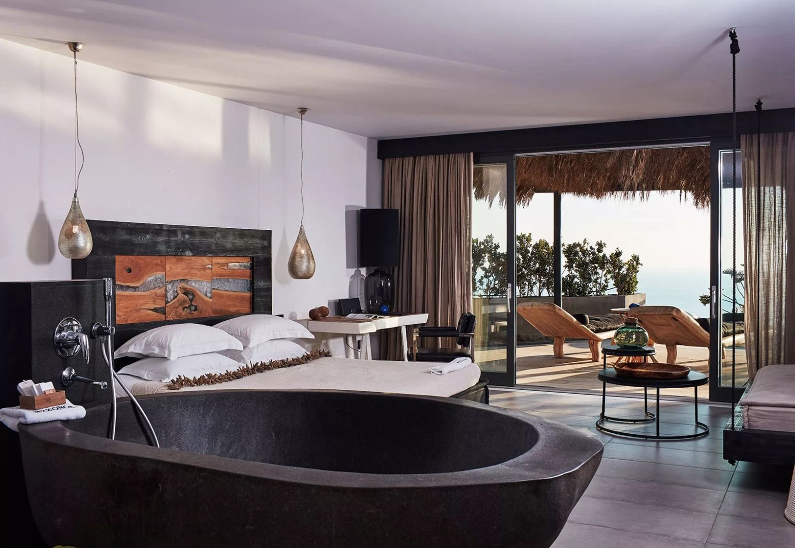 Blick aus dem Hotelzimmer über eine freistehende Wanne hinaus auf die Terrasse und das Meer.