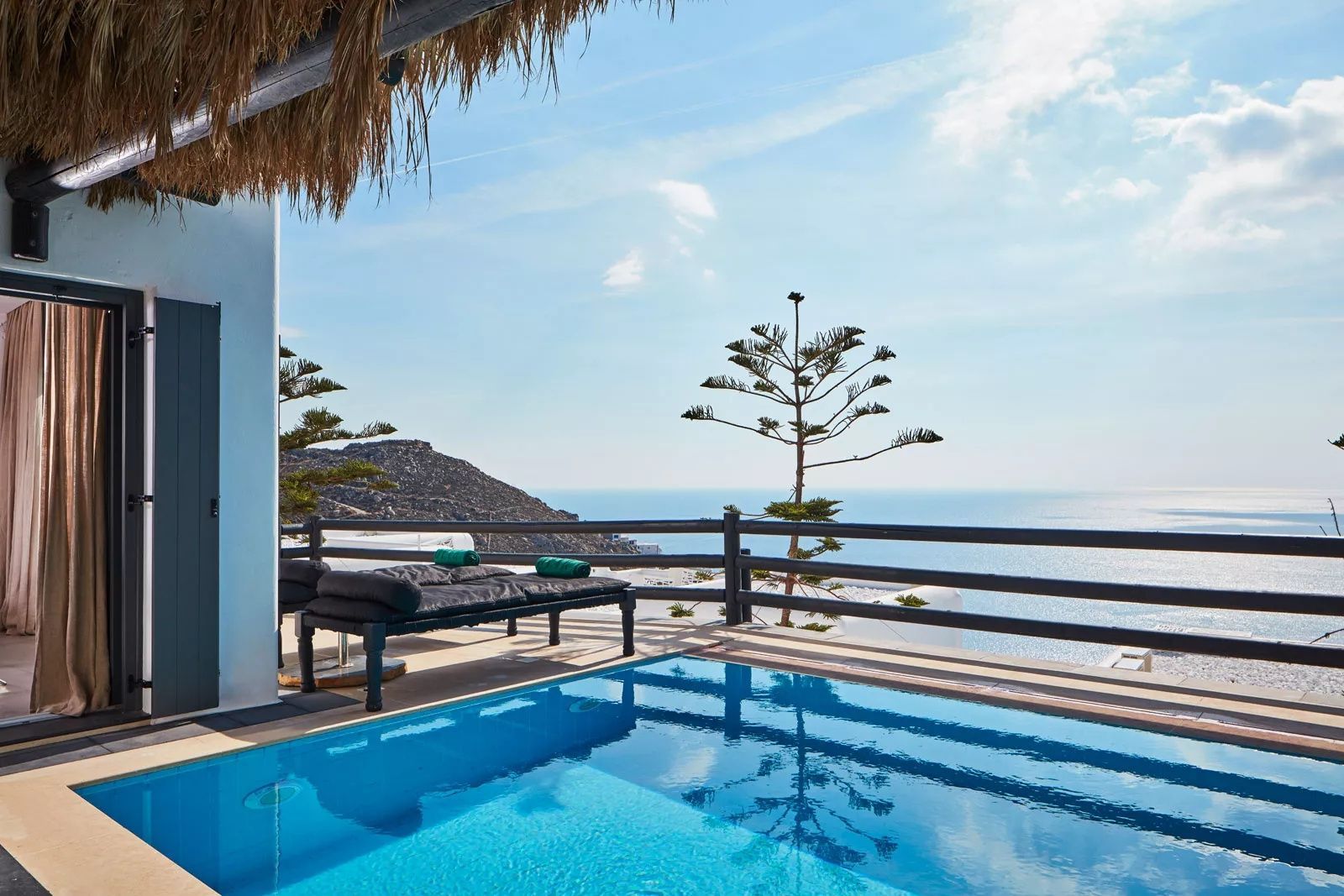 Private Poolterrasse mit Sonnenliegen und Blick über das blaue Meer.