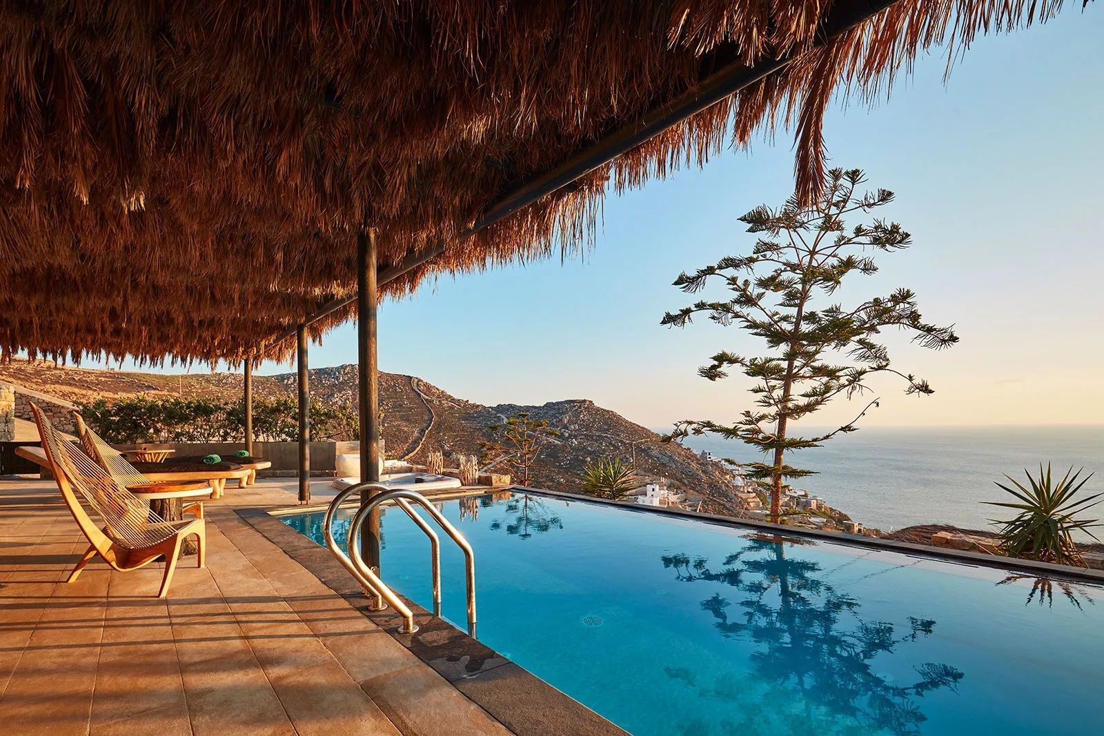 Ein Swimmingpool auf einer überdachten Terrasse mit Ausblick auf Felsen und das Meer.