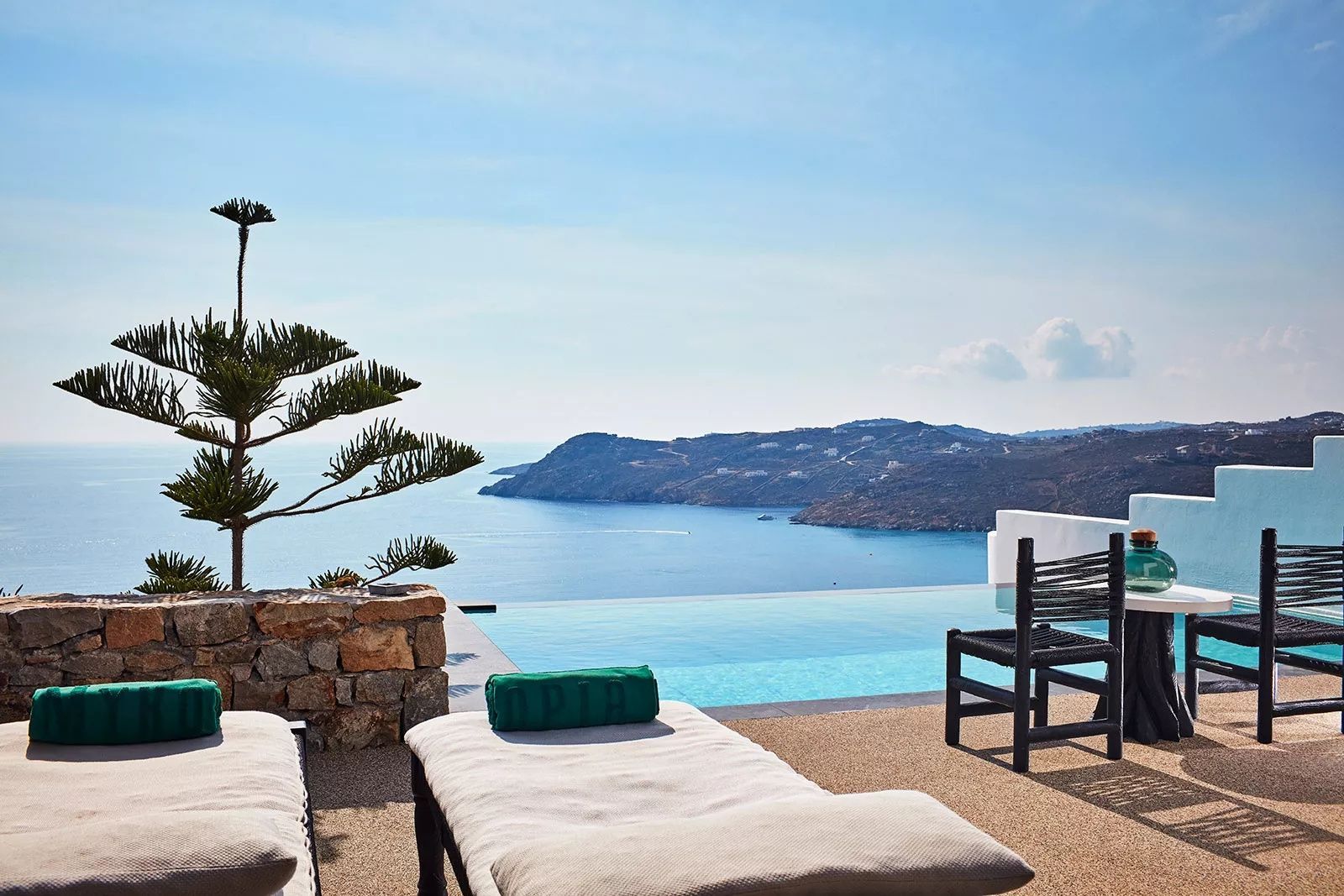 Infinitypool und Liegestühle auf einer Terrasse mit Blick auf die Bucht.