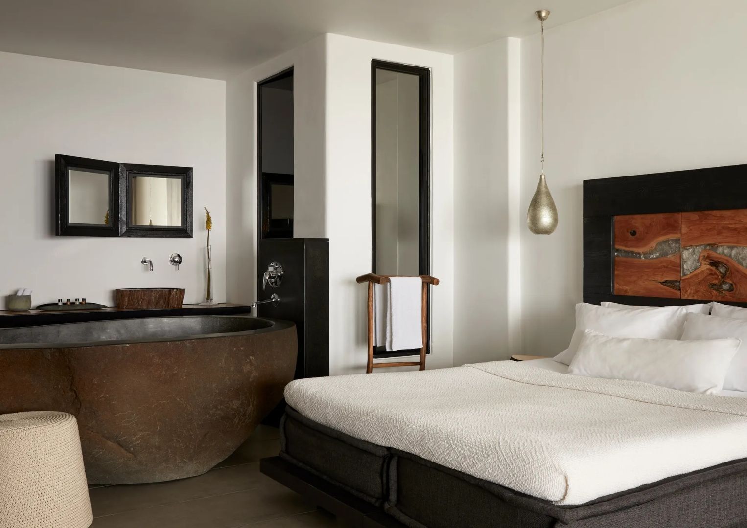 Schlafzimmer mit großem Doppelbett und einer freistehenden runden Badewanne aus Stein.