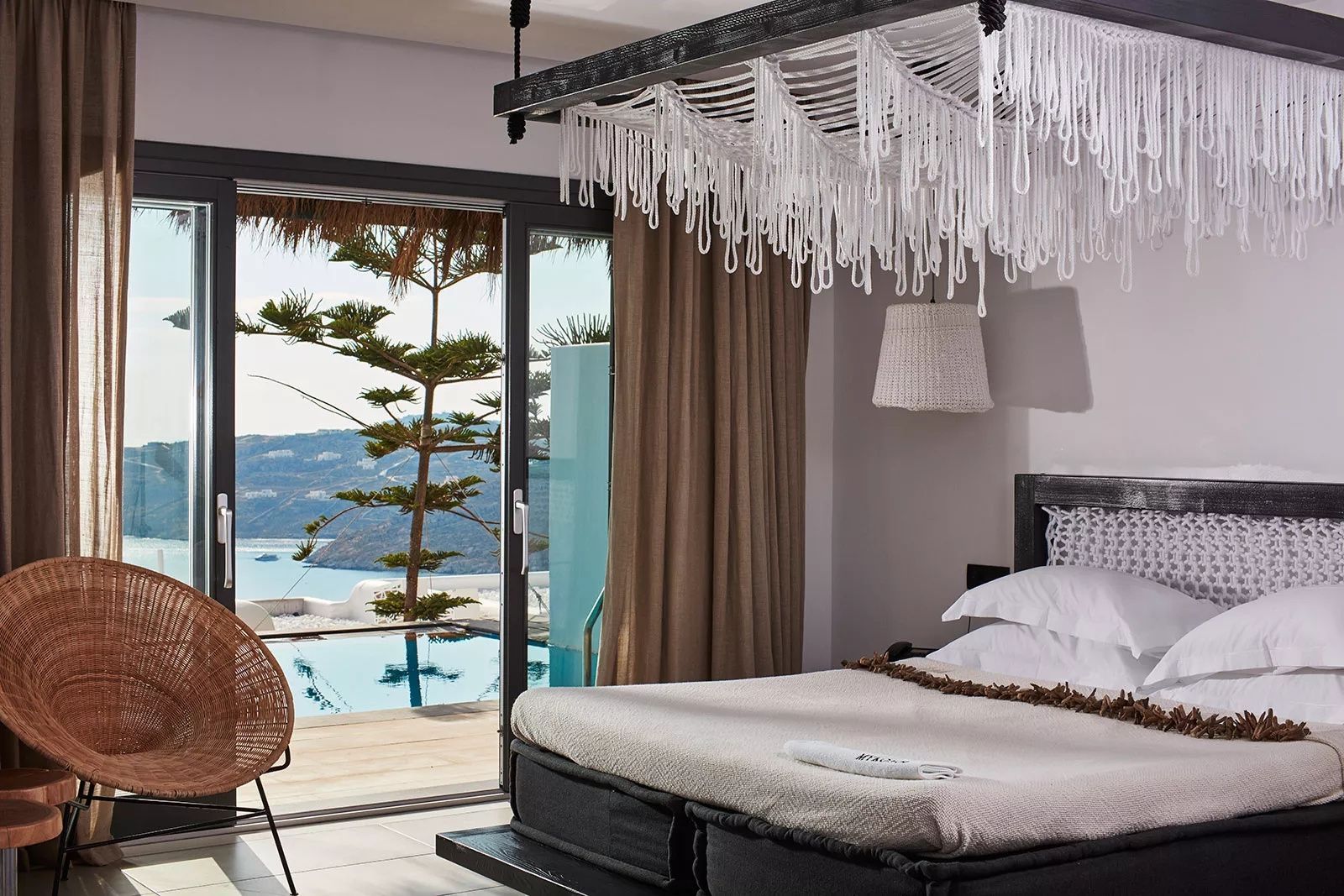 Schlafzimmer mit Himmeldekoration und Glasfront zur Terrasse mit privatem Pool.