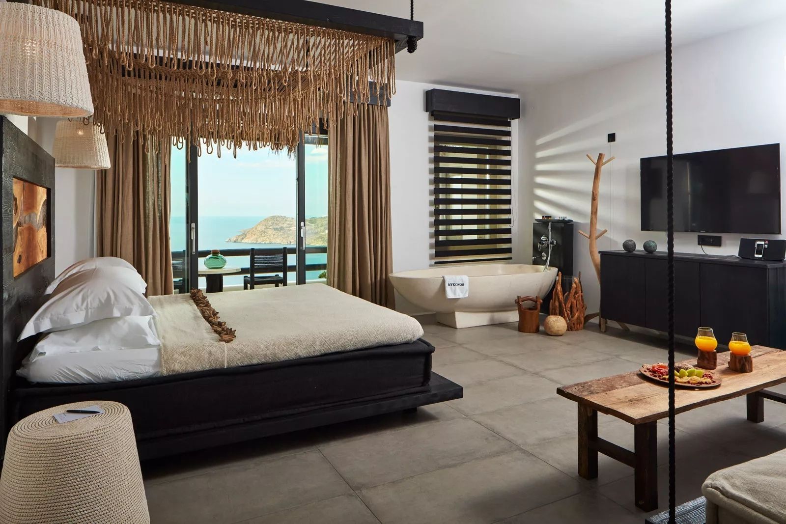Geräumiges Hotelzimmer mit großem Doppelbett, freistehender Badewanne und Balkon zum Meer.