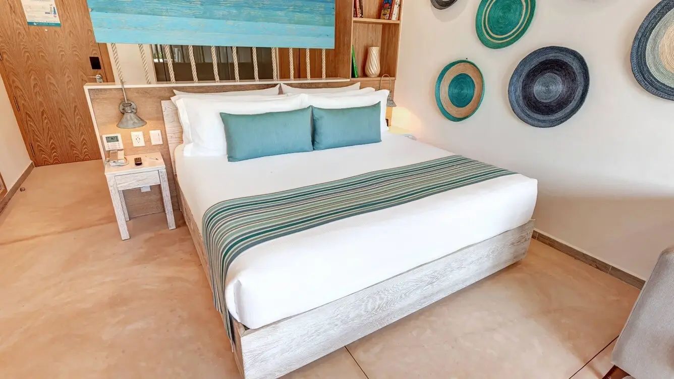 Doppelbett mit blauen Accent-Kissen und runden Wanddekorationen im Hotelzimmer.