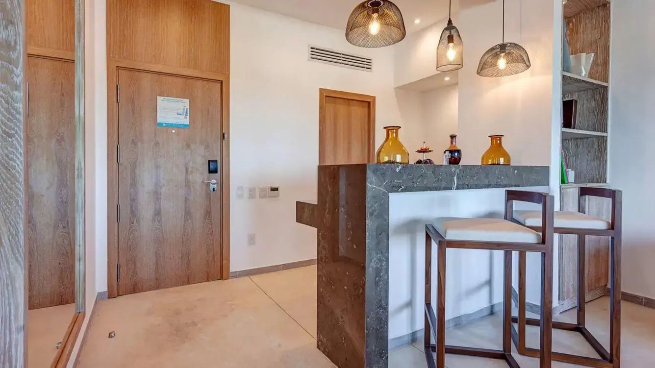 Theke aus dunklem Marmor mit Barhockern und modernen Hängeleuchten im Zimmer.
