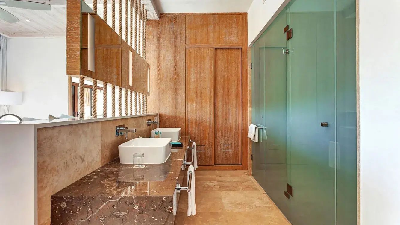 Badezimmer mit Naturstein-Waschtisch, Aufsatzwaschbecken und Glaskabine.