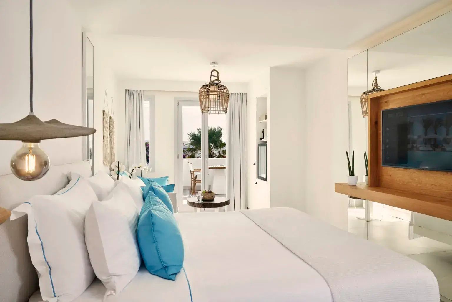 Modernes Schlafzimmer in Weiß mit Holzelementen und Blick auf die Terrasse.