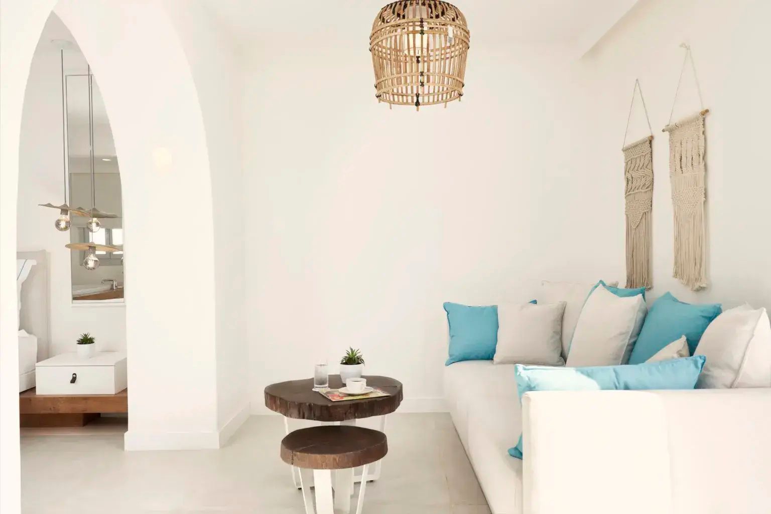 Sitzecke in Weiß und Blau mit einem Sofa, Flechtlampe und einem kleinen runden Holztisch.