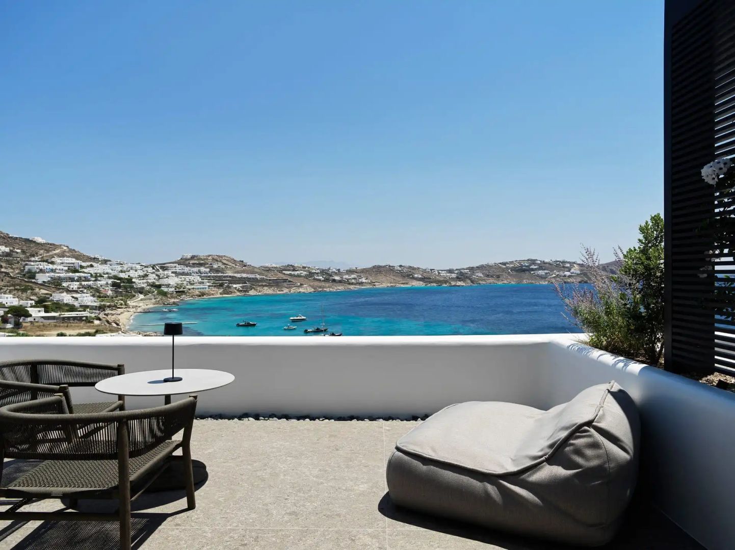 Möblierte Terrasse mit Sitzgelegenheiten und Aussicht auf die blaue Bucht.