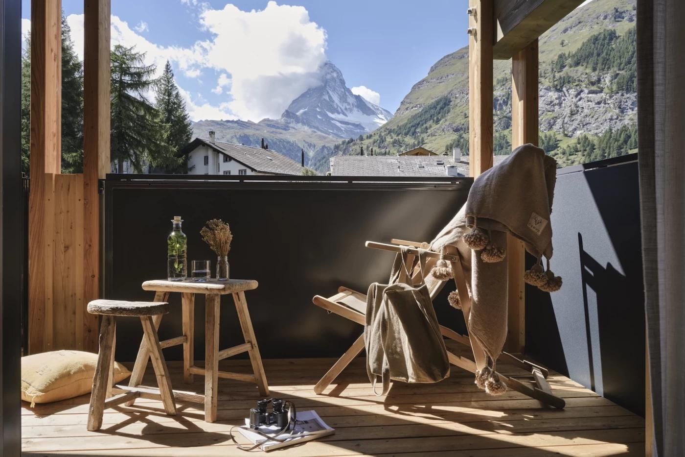 Balkon mit Holzstühlen und direktem Blick auf das Matterhorn in den Bergen.