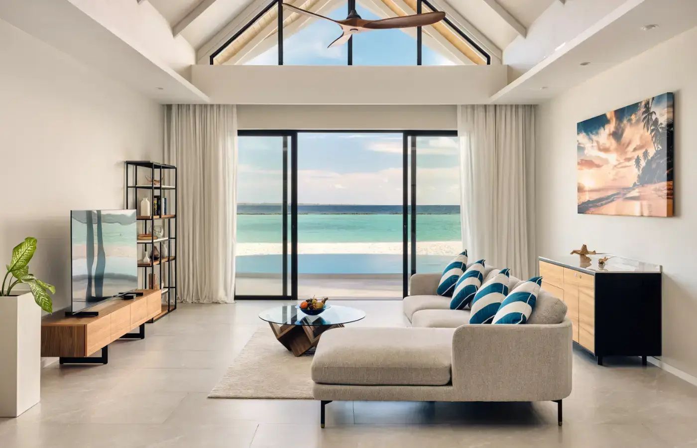 Geräumiges Wohnzimmer mit hellem Ecksofa, blau gestreiften Kissen und direktem Blick auf den Strand.