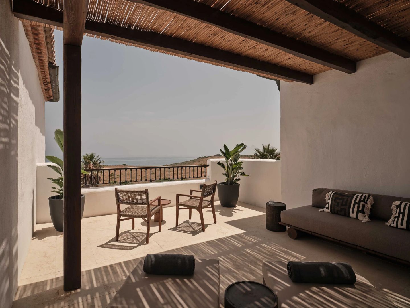 Sonnige Terrasse mit Stühlen und Panoramablick auf das Meer und die Landschaft.