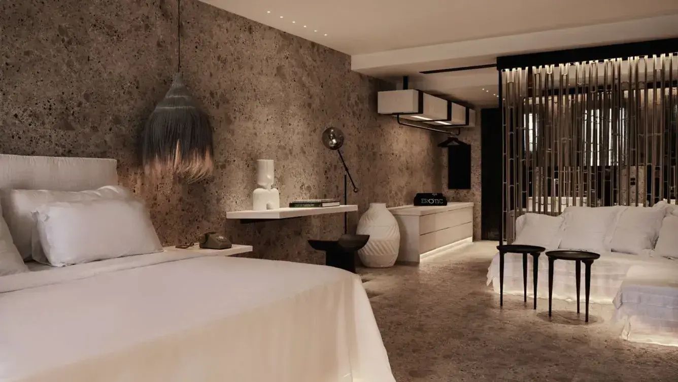 Innenansicht eines Hotelzimmers mit Steinwand, Hängelampe und dezenter Beleuchtung.