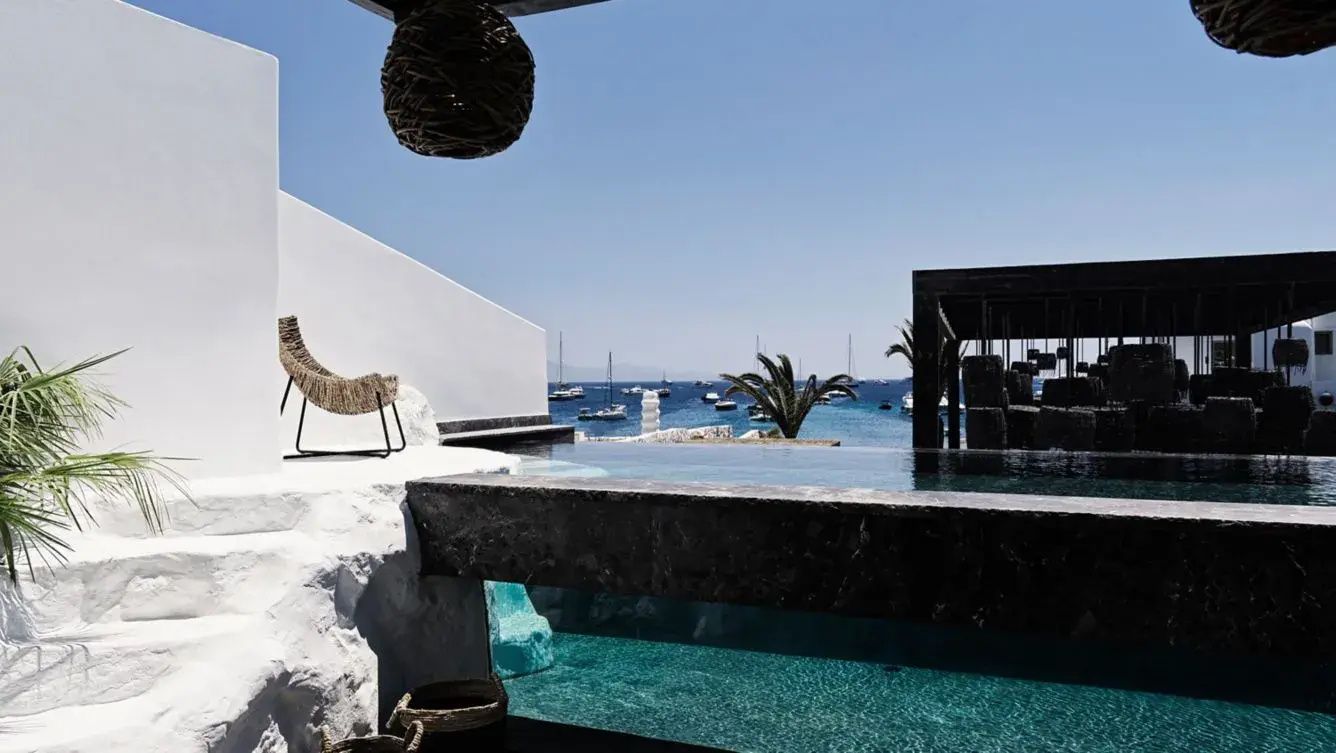 Privater Pool auf einer Terrasse mit Blick auf das Meer und verankerte Boote.