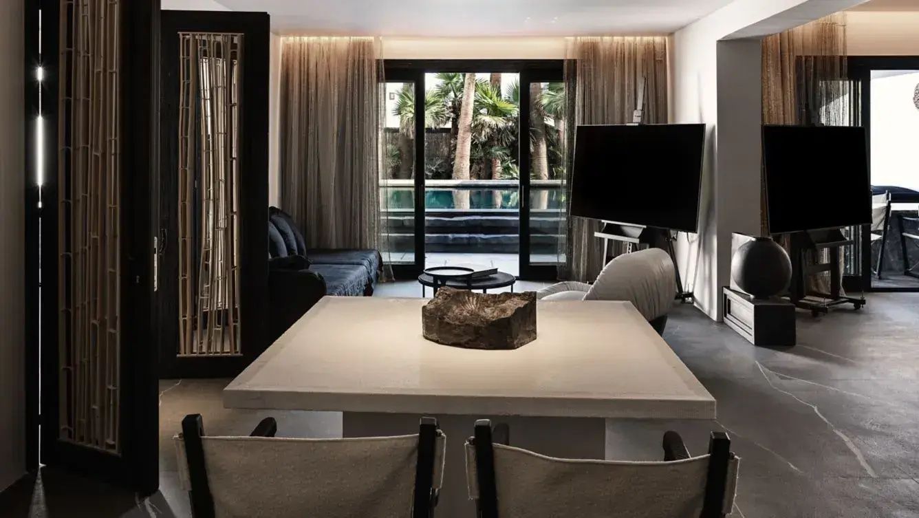 Helles Wohnzimmer in der Suite mit Essplatz im Vordergrund und Zugang zur Terrasse.