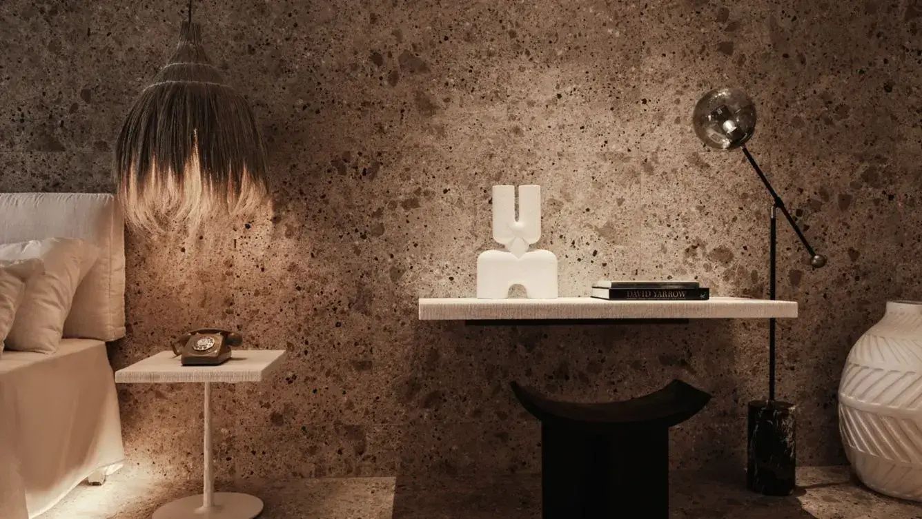 Nahaufnahme eines Wandregals mit weißer Skulptur vor einer Wand in Natursteinoptik.