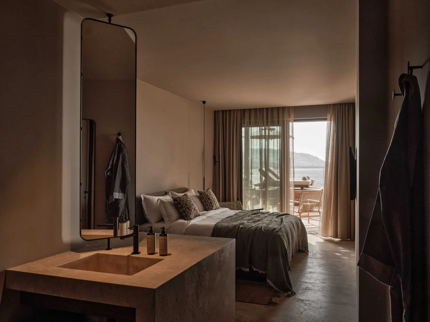 Hotelzimmer mit Doppelbett, offenem Waschtisch und Balkonzugang mit Meeresblick.