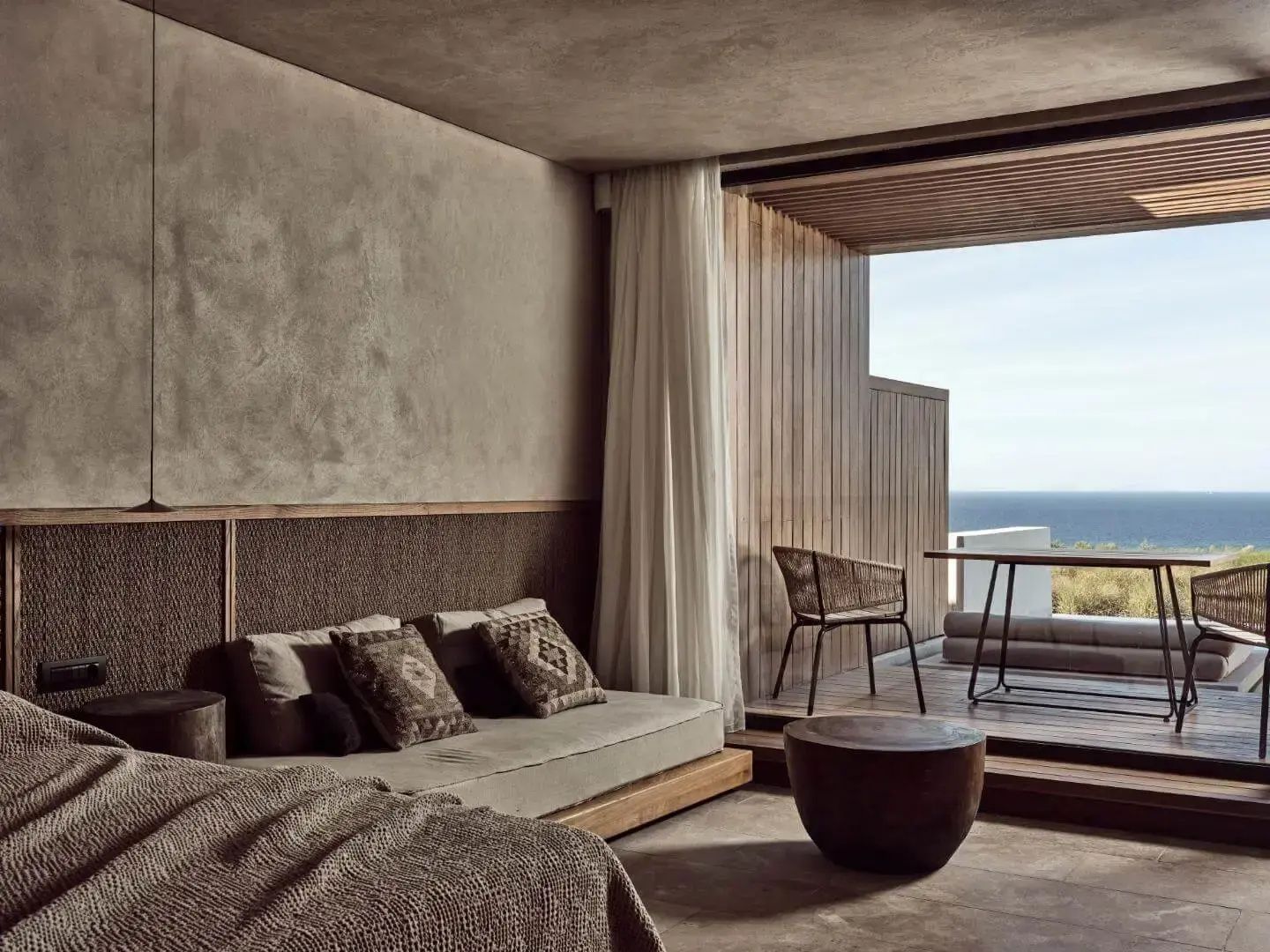 Helles Zimmer mit niedriger Sitzbank und Holzdekor sowie einer Terrasse mit Meerblick.