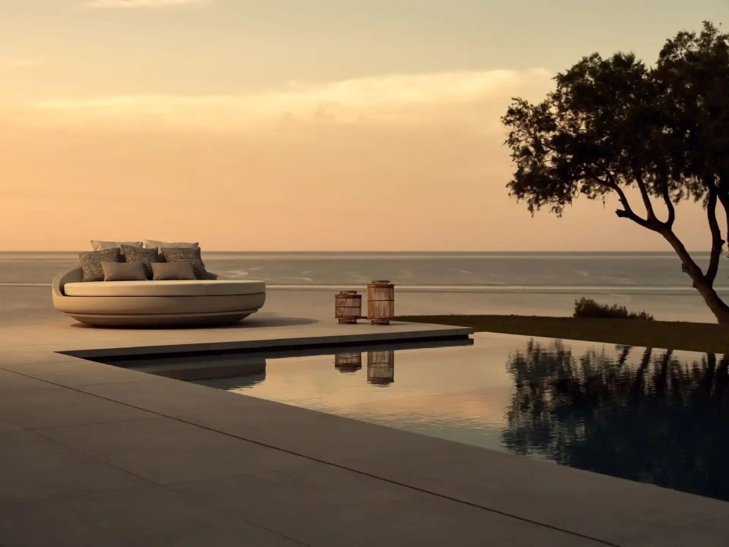 Terrassenbereich am Infinitypool mit einem runden Tagesbett und Blick auf das ruhige Meer.