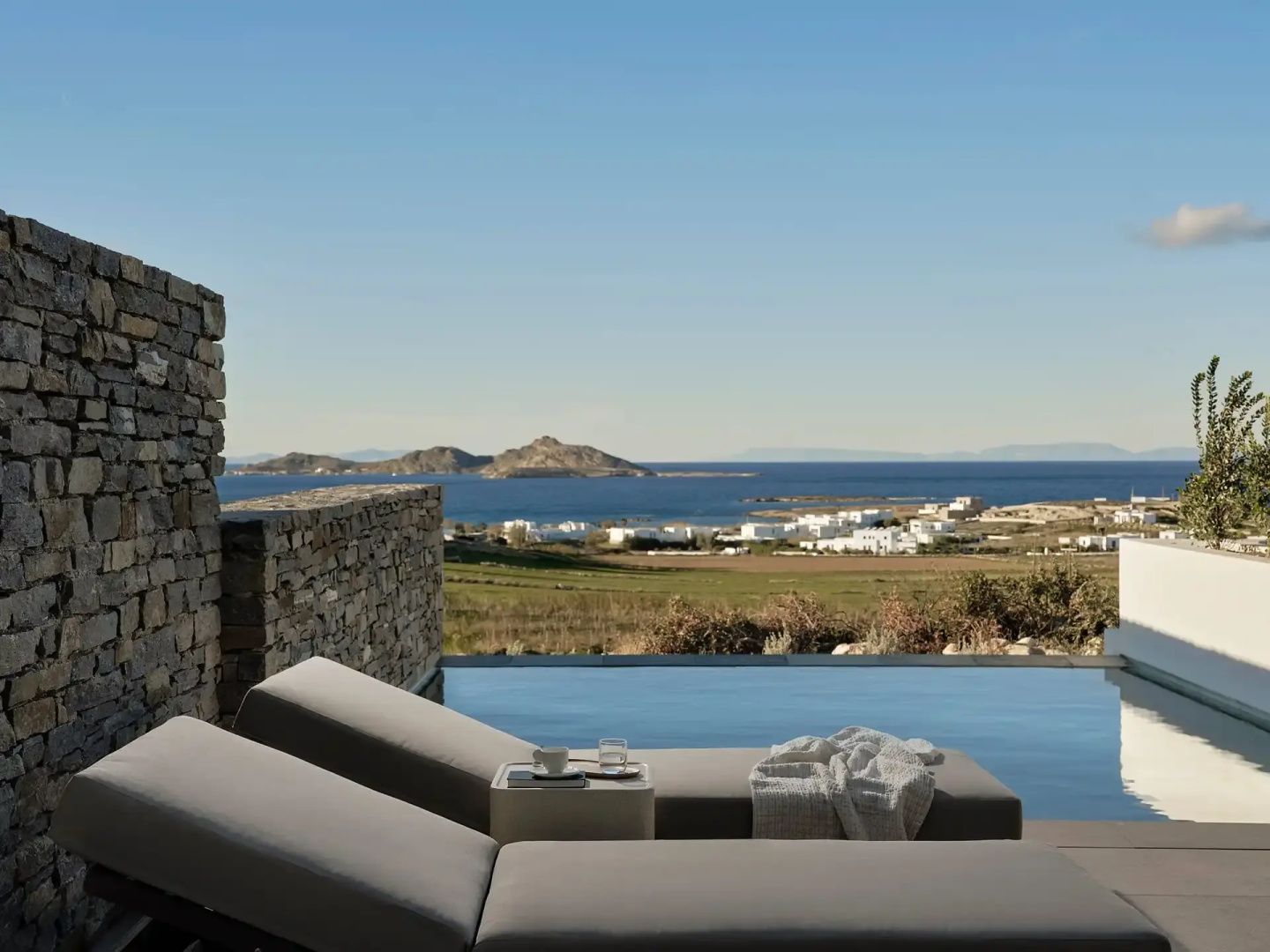 Ausblick von der Terrasse mit Sonnenliegen auf die Landschaft und das Meer.