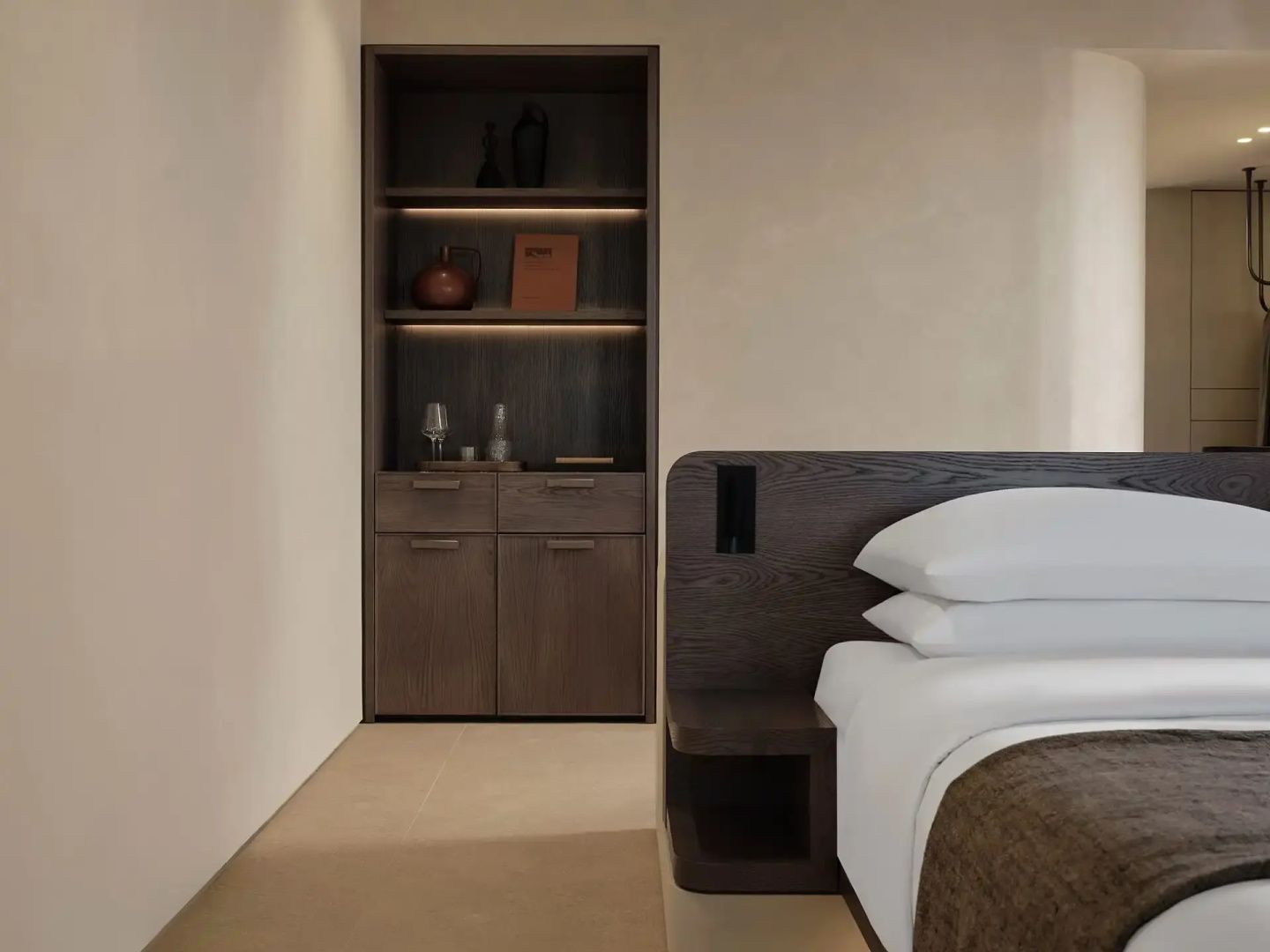 Bett mit dunklem Holzkopfteil und integriertem Schrankbereich im Hotelzimmer.