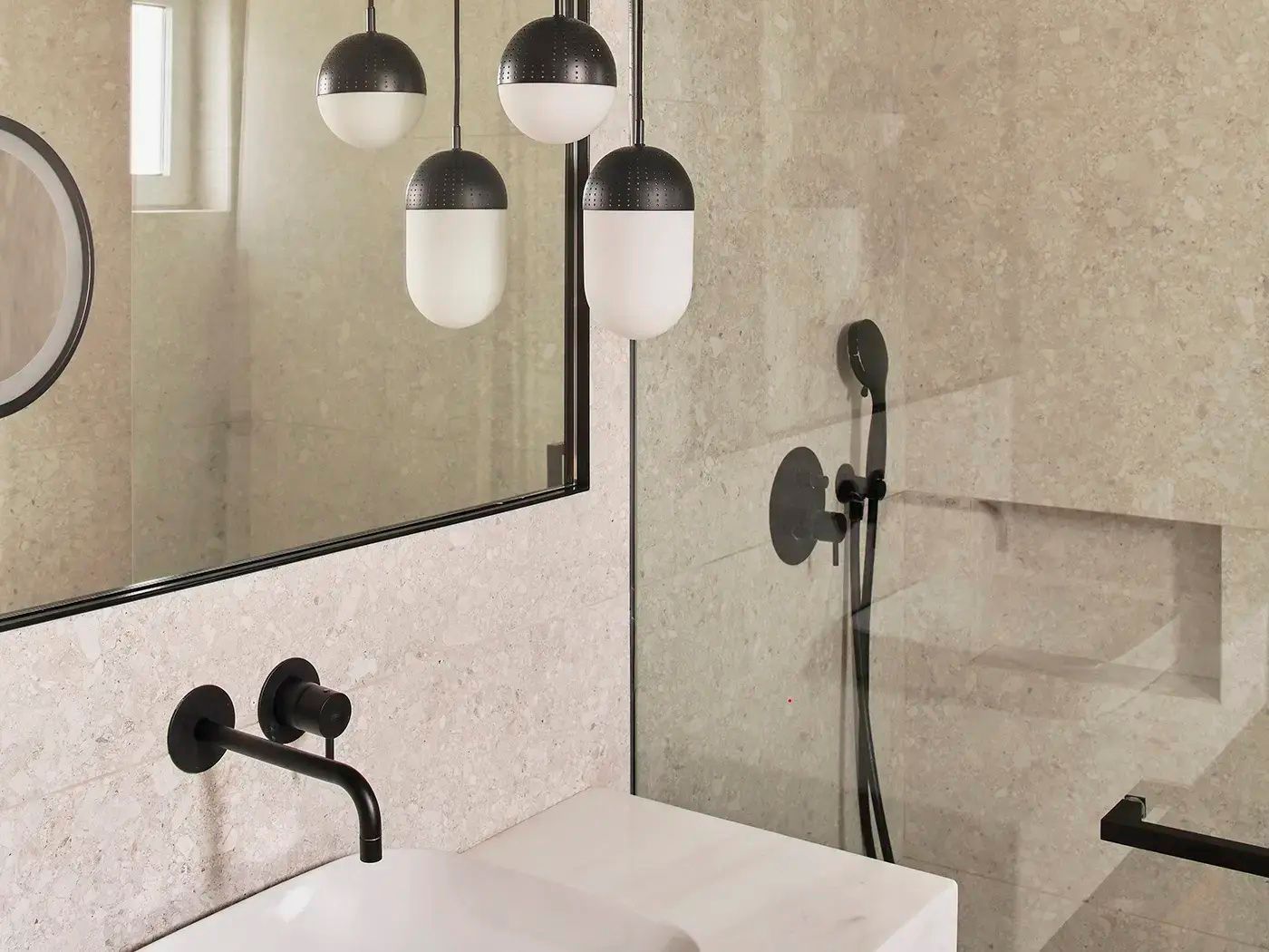 Badezimmer mit weißem Waschbecken, schwarzer Armatur, Spiegel und Glasdusche.