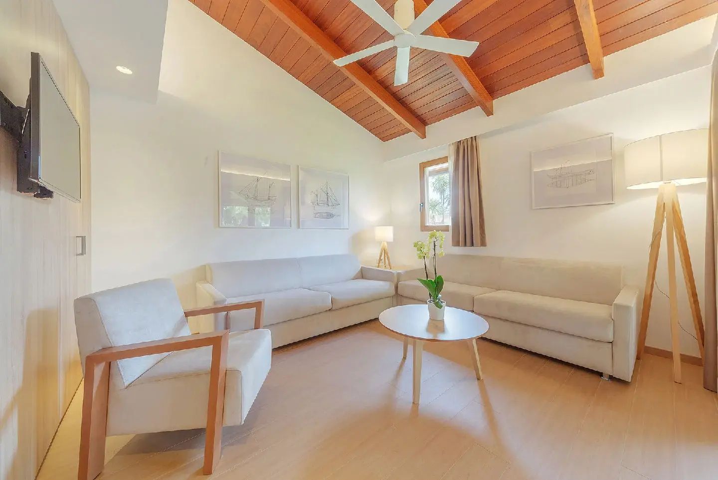 Wohnbereich einer Suite mit hellen Sofas, Sessel, Couchtisch und Holzdecke mit Ventilator.