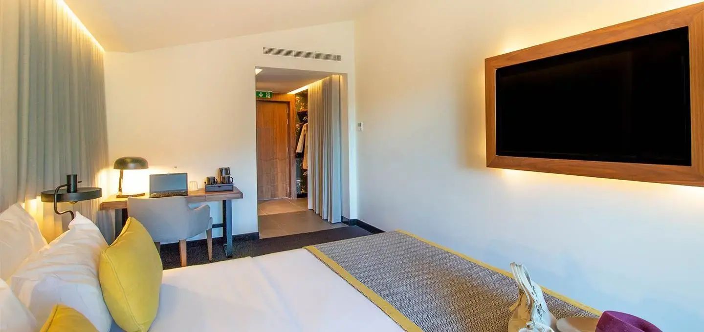 Blick durch das Hotelzimmer auf den Eingangsbereich, den Schreibtisch und Fernseher