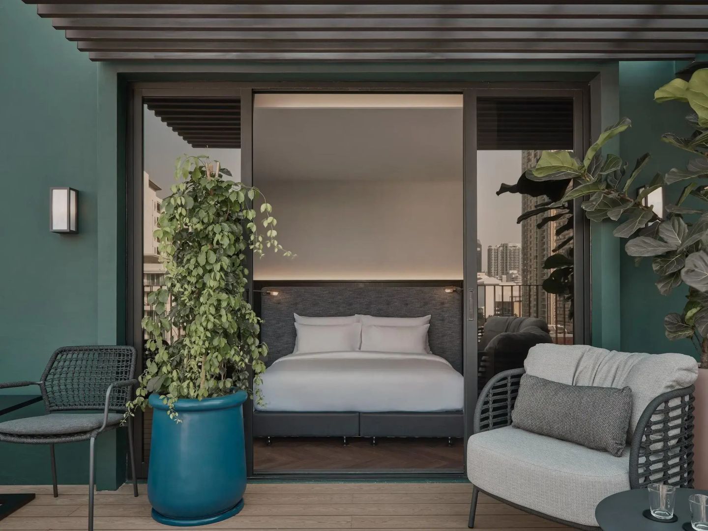 Überdachte Terrasse mit einem blauen Pflanzkübel, Sitzgelegenheiten und Zugang zum Zimmer.