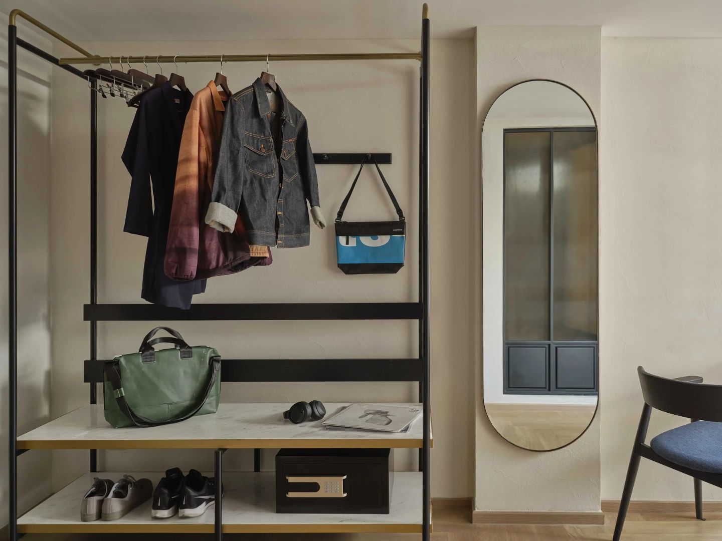 Garderobenbereich im Zimmer mit offener Kleiderstange, Ablagen für Gepäck, Schuhen und Wandspiegel.