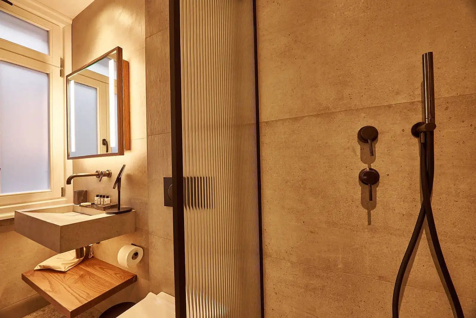 Badezimmer mit geriffelter Glastrennwand an der Dusche und hellem Waschtisch.
