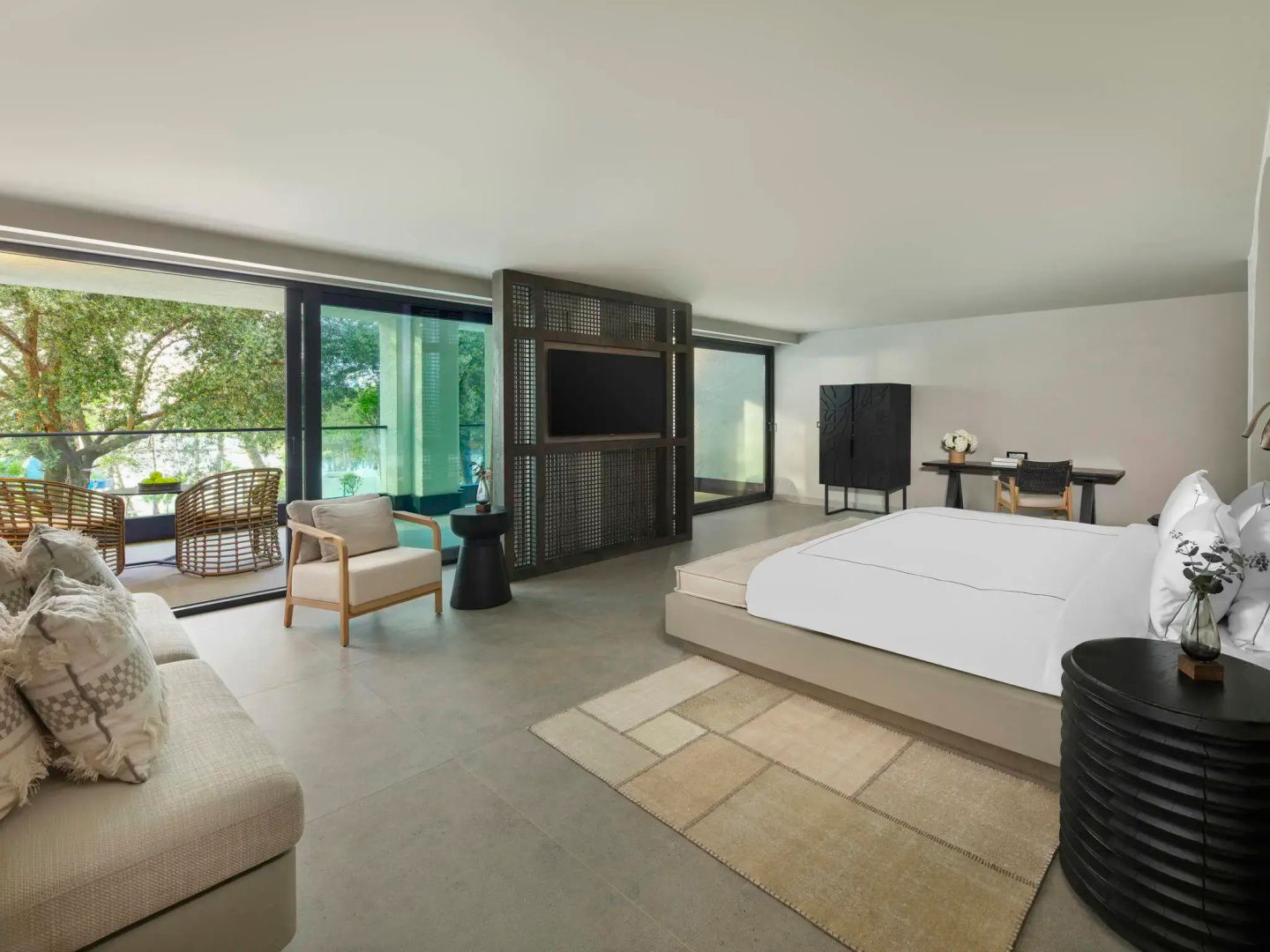 Modern eingerichtetes Hotelzimmer mit Doppelbett, Sitzbereich und Zugang zur Terrasse.