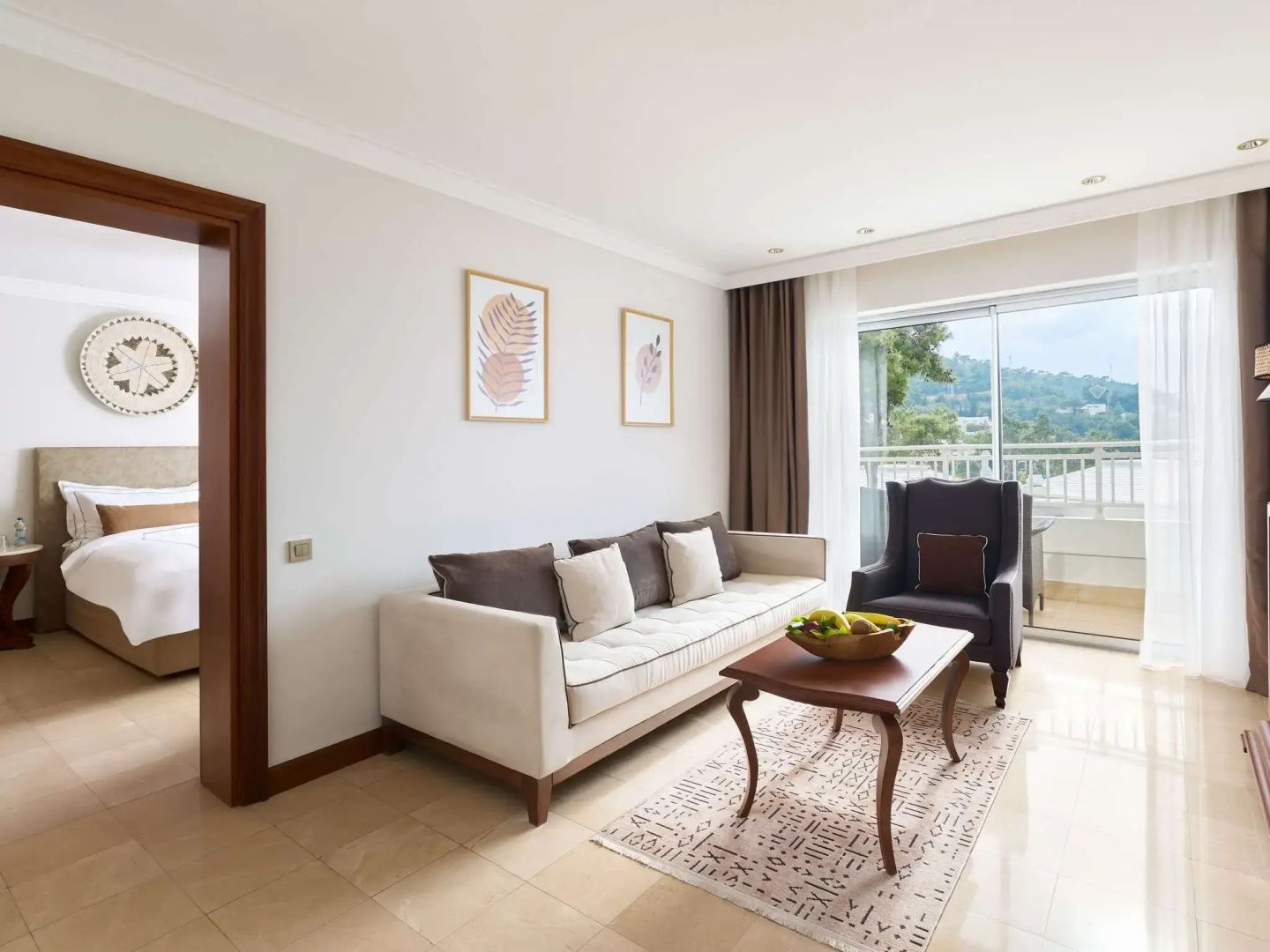 Wohnbereich einer Suite mit Sofa, Sesseln, Couchtisch und Blick auf den Balkon.