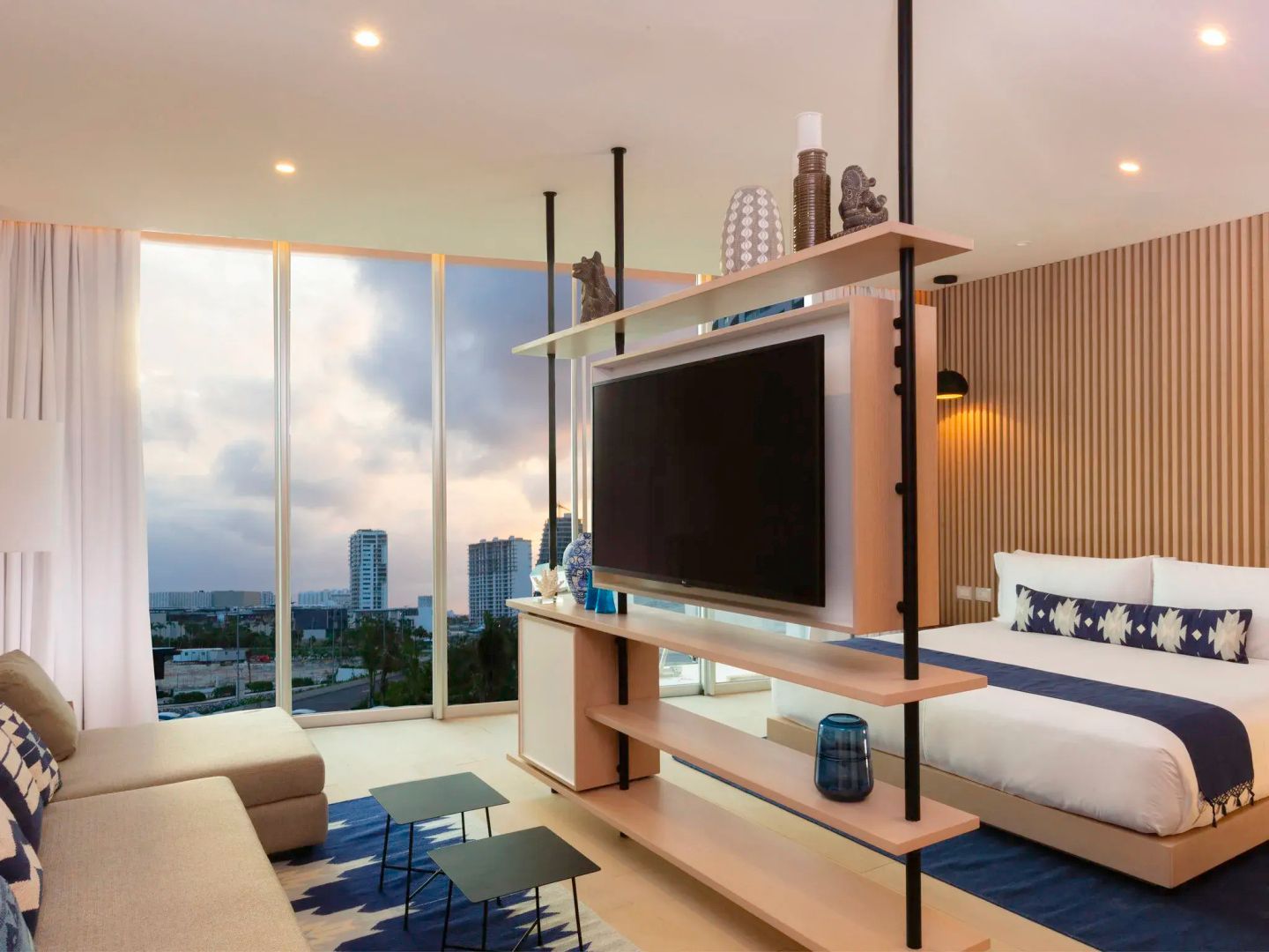 Raumteiler mit Fernseher zwischen Sitzbereich und Schlafbereich neben Panoramafenster
