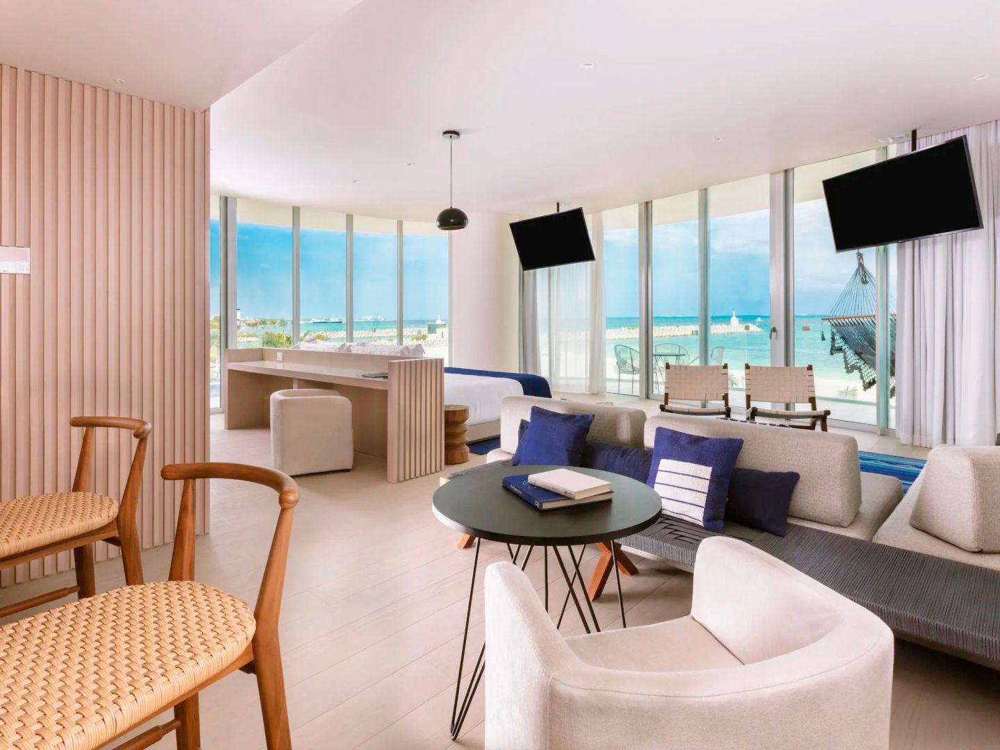 Offener Wohnbereich einer Suite mit Sitzgelegenheiten und Panoramablick auf das Meer.