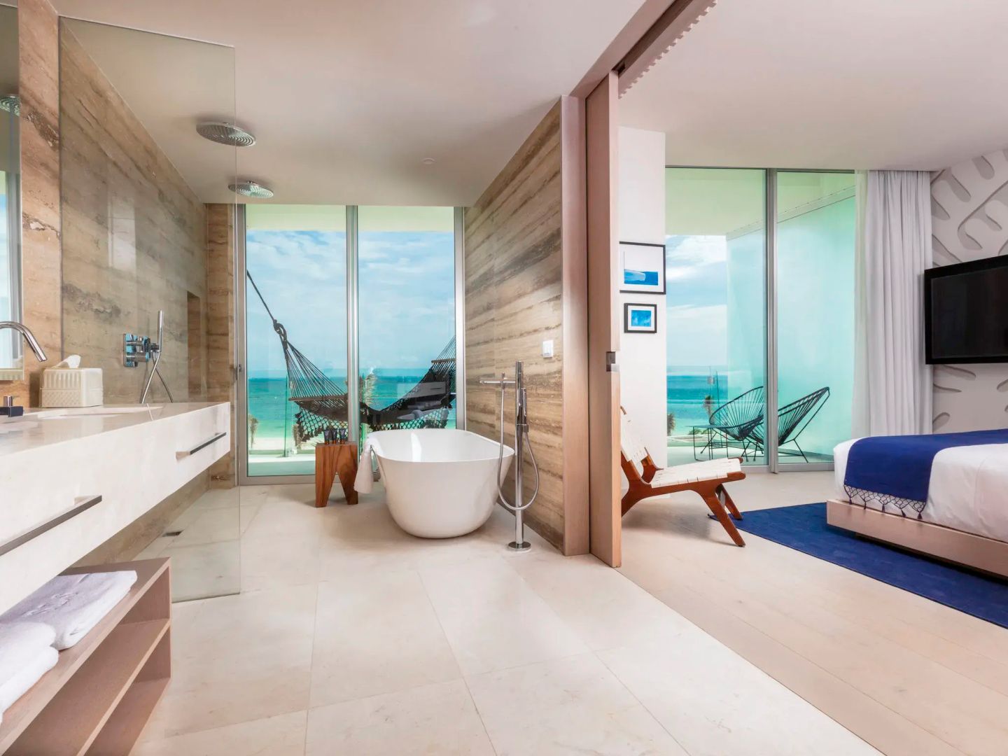Badezimmer mit freistehender Badewanne, Waschtisch und Meerblick durch die große Fensterfront.
