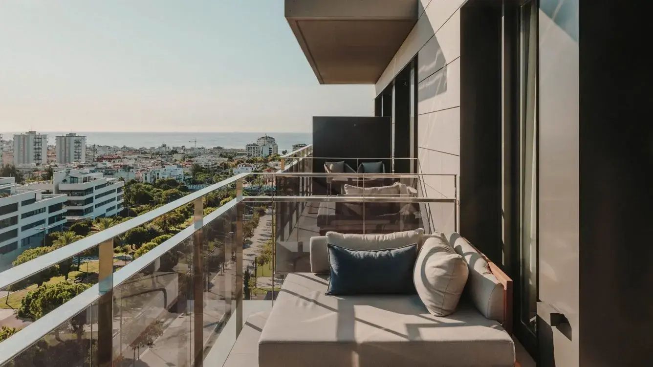 Balkon mit einem Liegesofa und Weitblick auf die Stadt und das Meer.
