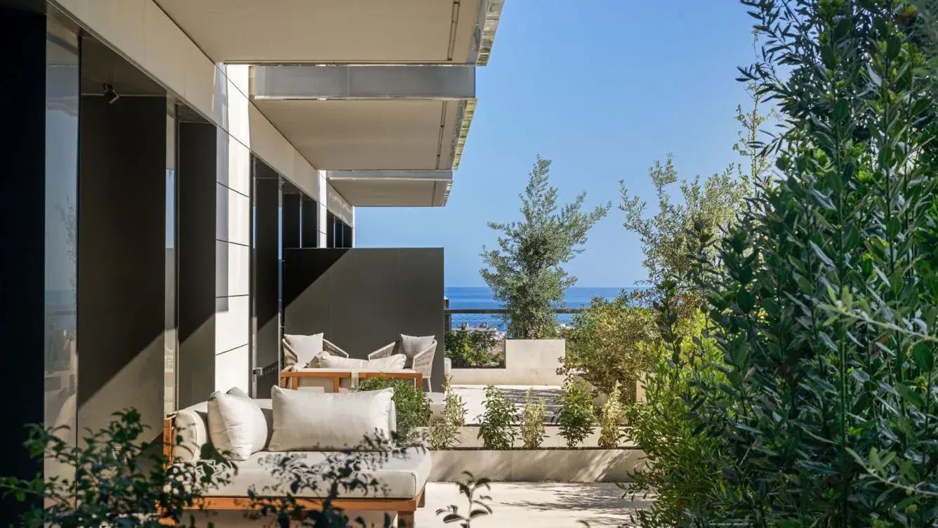 Terrasse mit Sitzmöbeln, Bepflanzung und freiem Ausblick auf das Meer.
