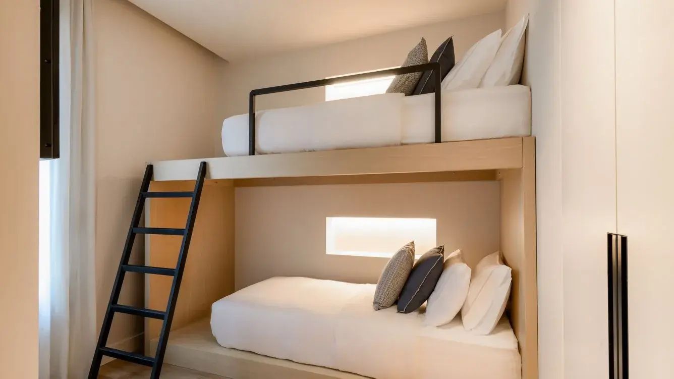 Integriertes Etagenbett aus hellem Holz mit weißer Bettwäsche.