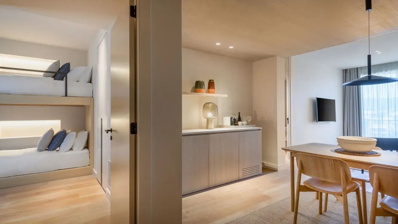 Heller Wohnbereich einer Suite mit Holzmöbeln, Anrichte und Tisch.